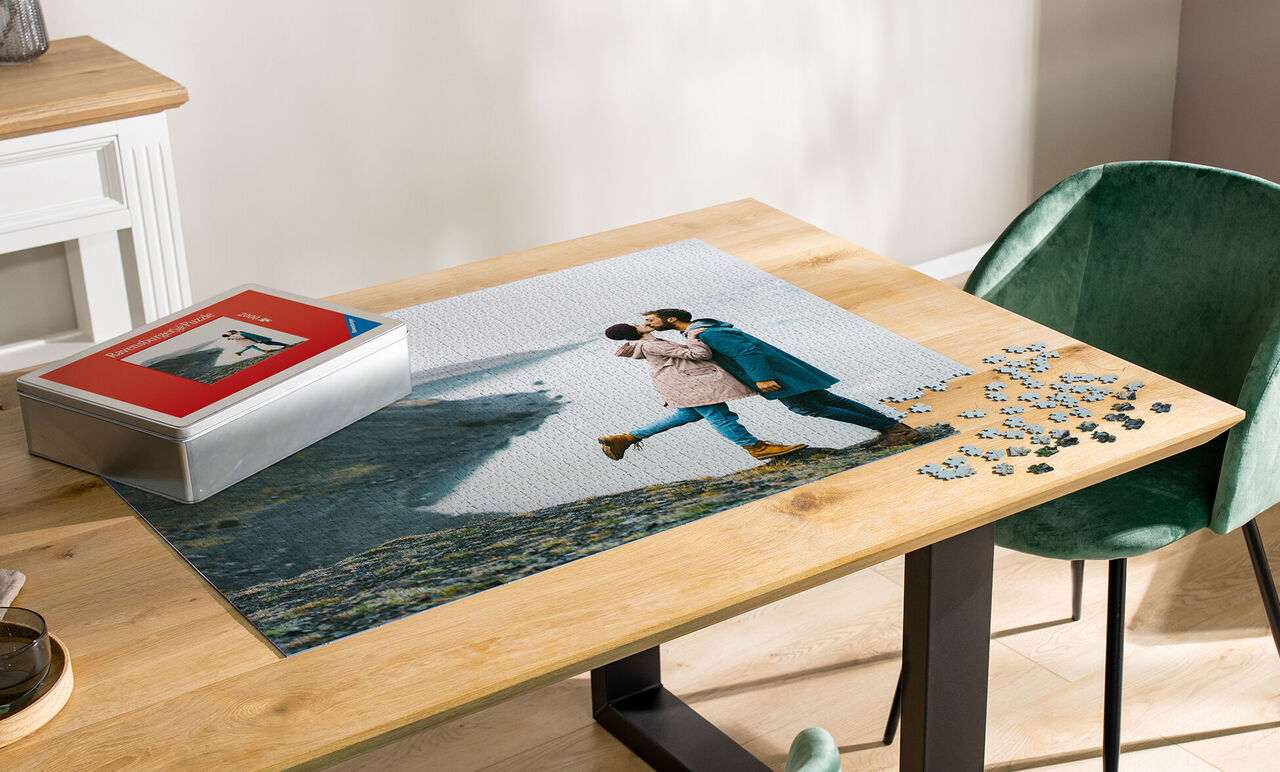 Una coppia si abbraccia su un grande puzzle fotografico su un tavolo di legno.