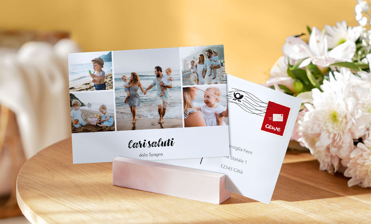 Due cartoline CEWE su un tavolo, una con immagini di vacanze in famiglia e l'altra con un francobollo.