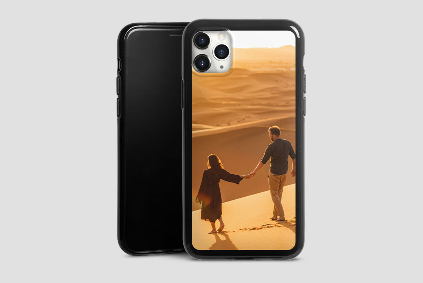 Una coppia passeggia mano nella mano tra dune di sabbia al tramonto.