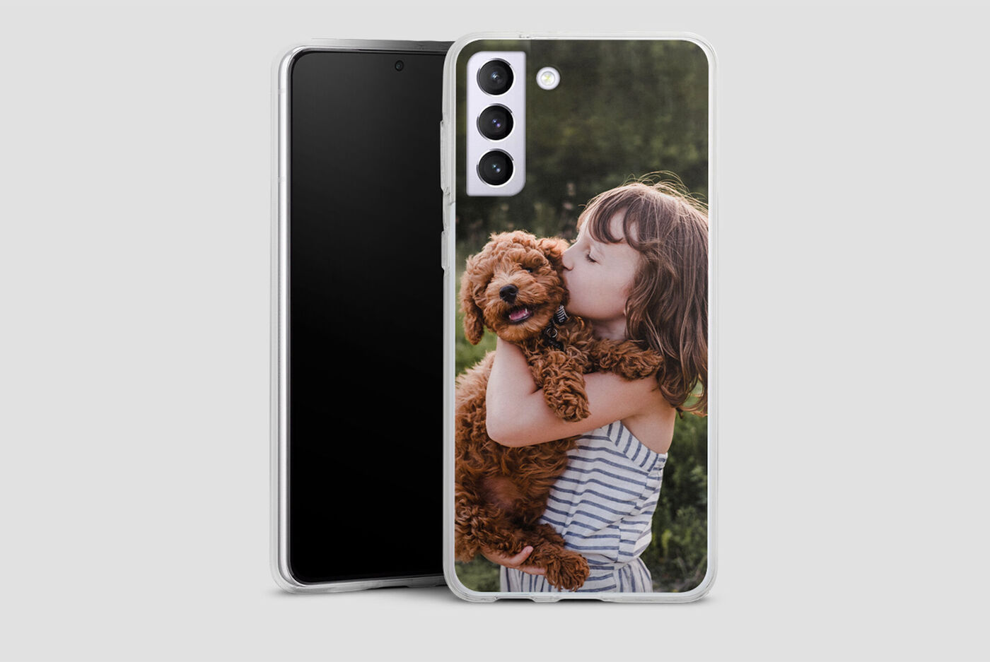 Ragazza tiene un cane felice tra le braccia, con uno smartphone sullo sfondo