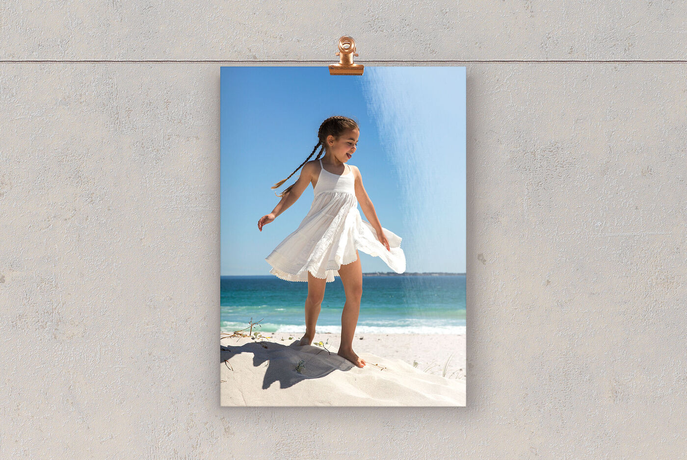 Una ragazza in un vestito bianco sta felice sulla spiaggia godendosi il sole.