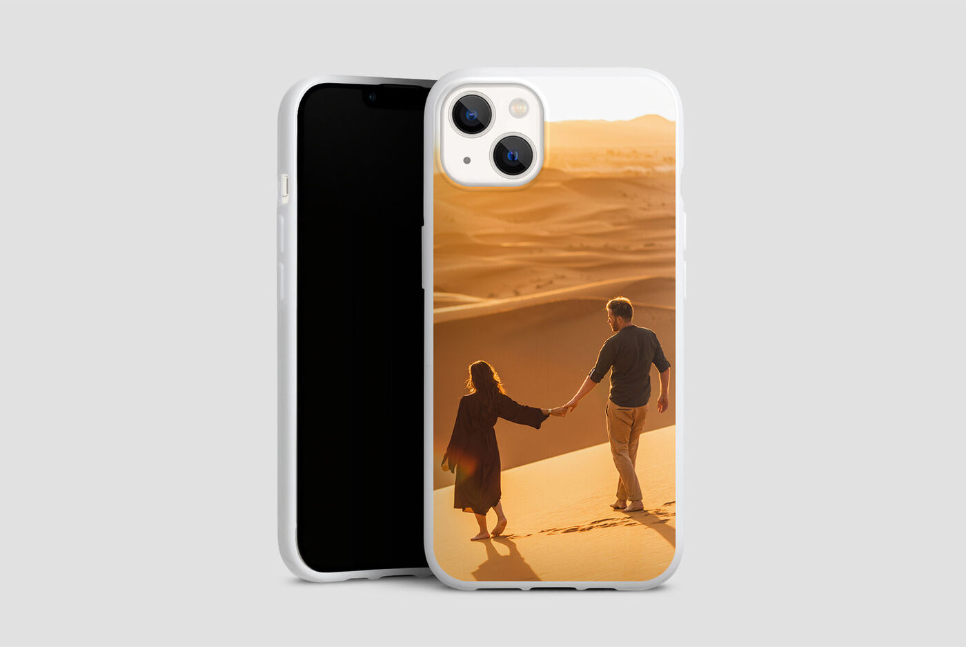 Una coppia si tiene per mano mentre passeggia tra le dune sabbiose al tramonto
