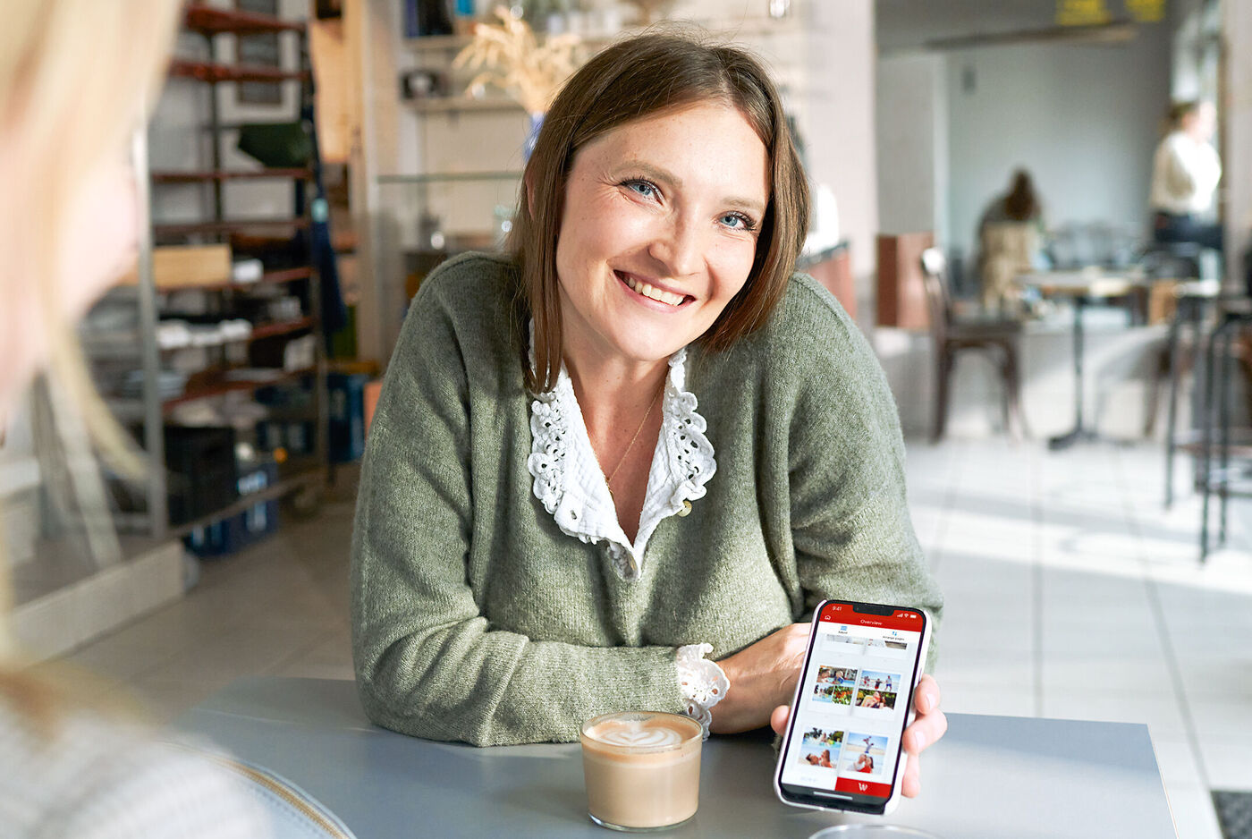 Una persona mostra sul proprio smartphone idee creative in un caffè accogliente.