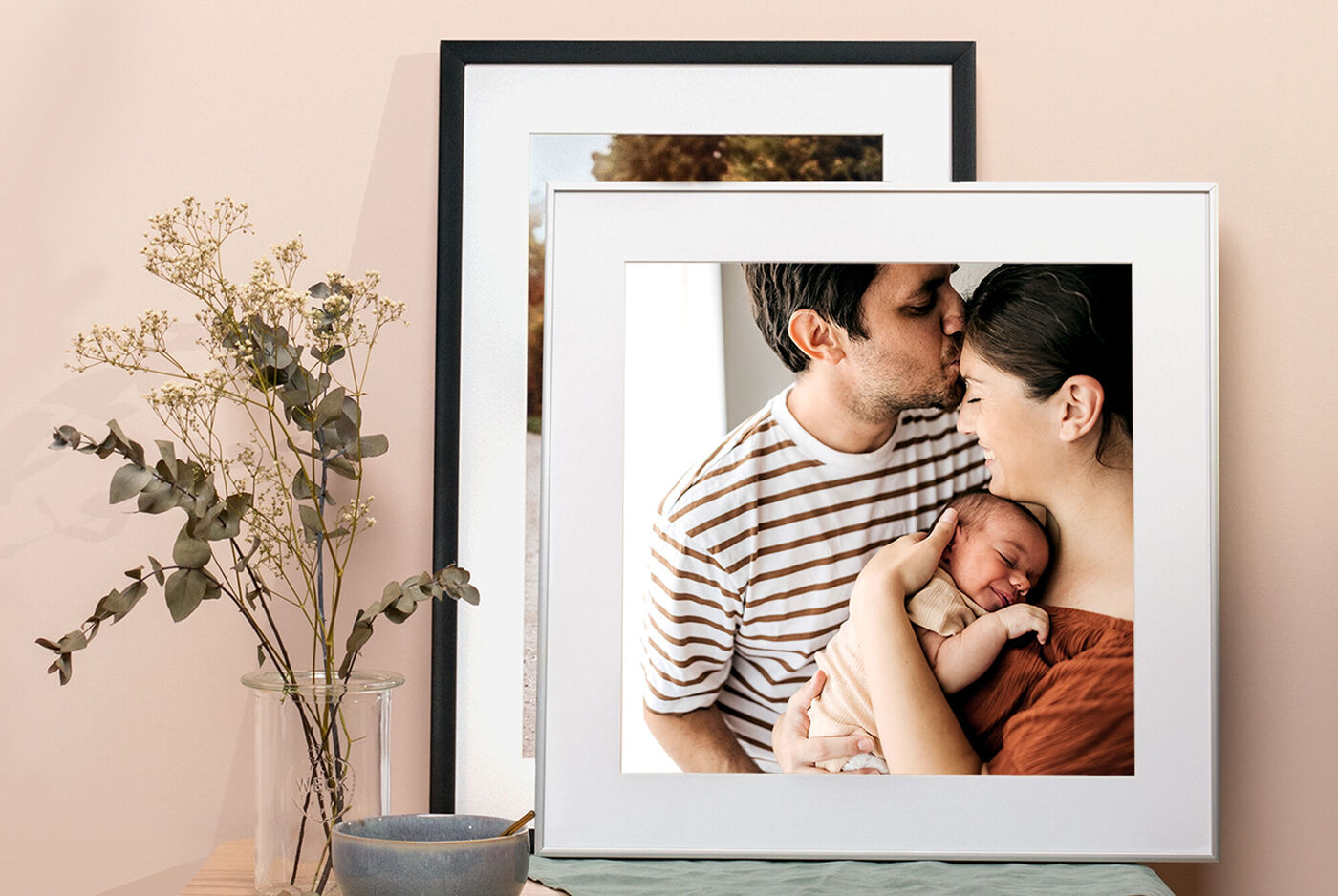 Una famiglia posa davanti a foto con il loro bambino, celebrando ricordi.