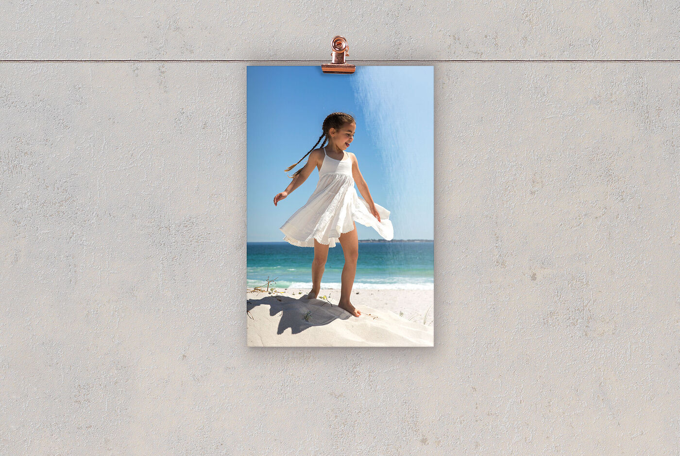 Un bambino in un vestito bianco gioca in spiaggia e gode del raggio di sole.