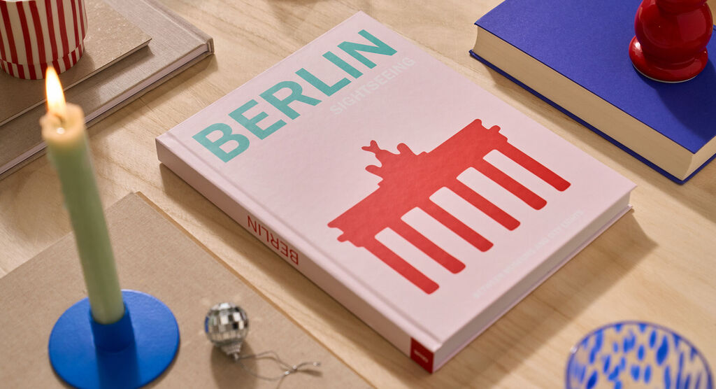 Un fotolibro CEWE è appoggiato su un tavolo. La copertina è rosa e riporta la scritta "Berlino".
