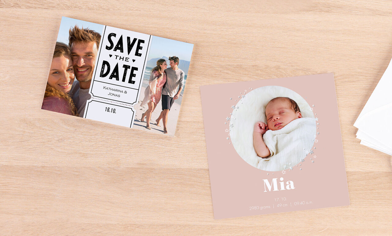 Un set di biglietti di CEWE, uno con "Save the Date" e l'altro con "Mia" su sfondo rosa, su un tavolo chiaro.