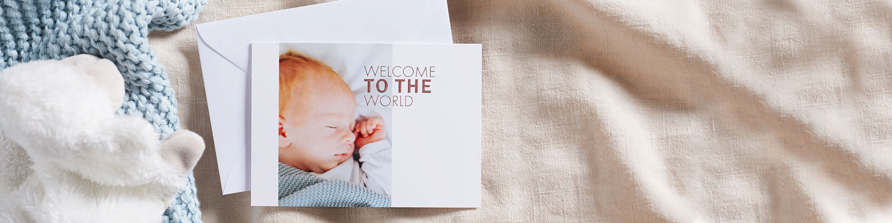 Una dolce cartolina per baby con il testo 'Benvenuto nel mondo' su uno sfondo chiaro con un tessuto morbido.