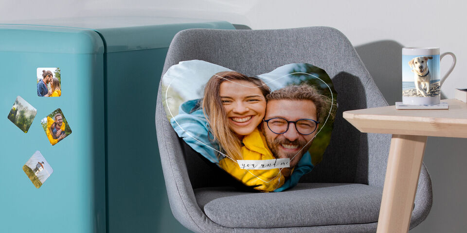 Cuscino a forma di cuore con un'immagine su una poltrona. Una tazza e un frigorifero sullo sfondo.