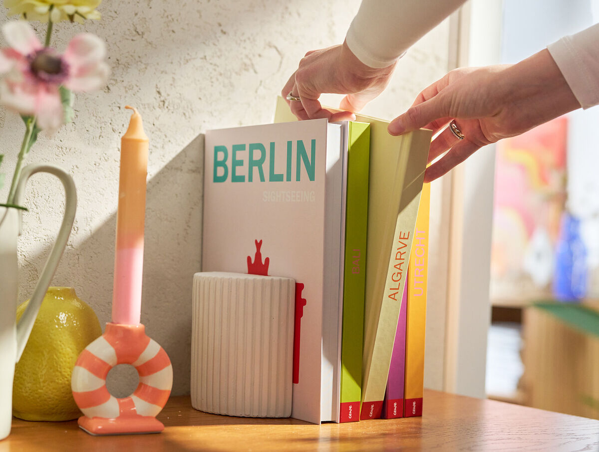 Un FOTOLIBRO Cewe è appoggiato su un tavolino da caffè. La copertina è rosa e riporta la parola "Berlin".